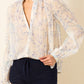 a sheer, long-sleeve button-up blouse by Alix Of Bohemia with a delicate blue and beige floral pattern